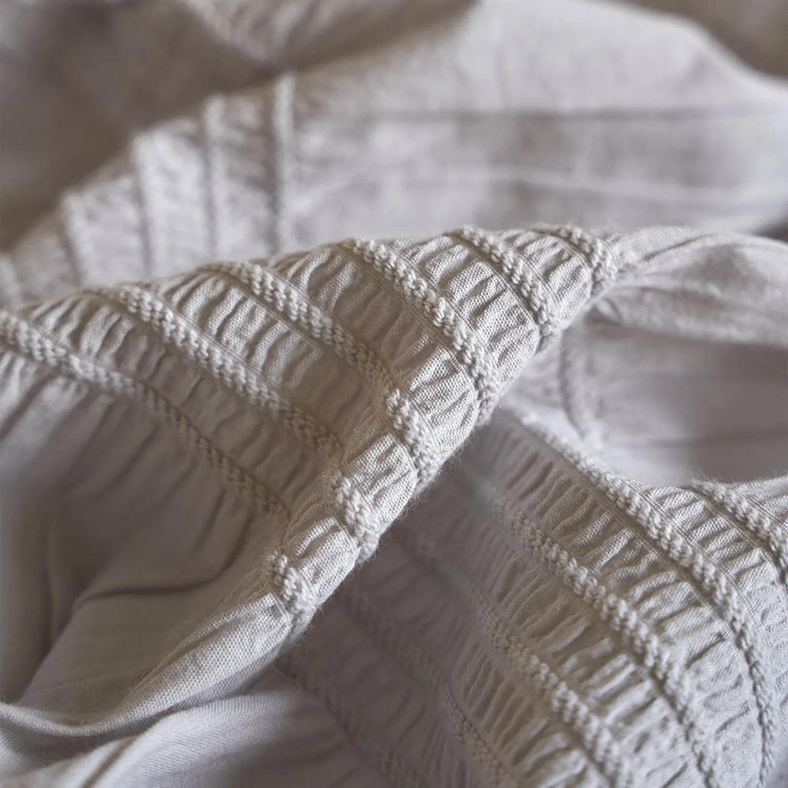 Extreme close-up on the smocked and ruched stitching of the Dove Grey cotton fabric.