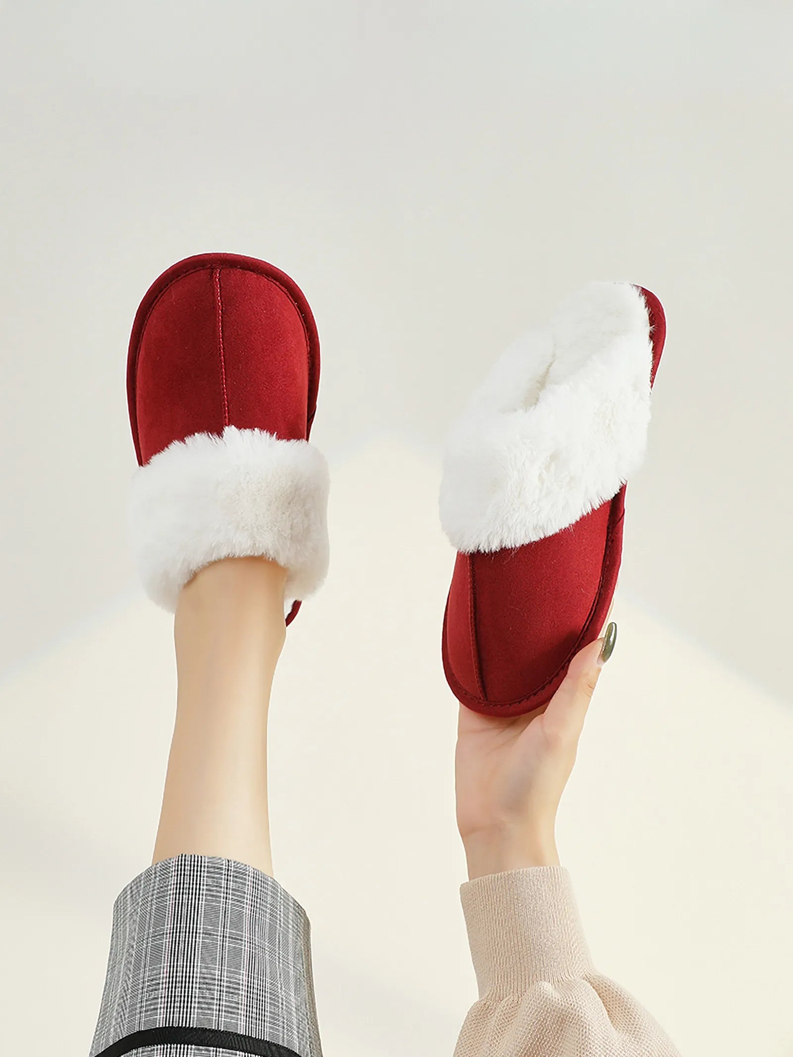 RoomDen Plush Solid Color Faux Suede House Slippers - Red variant held up against white background.