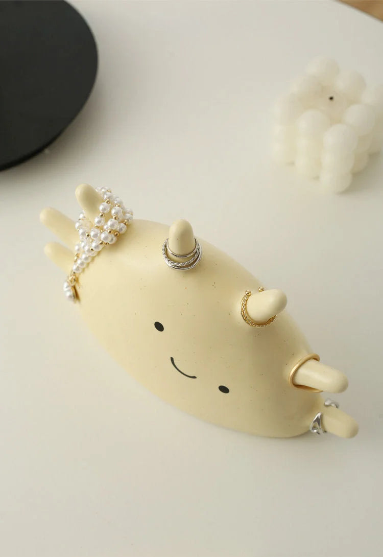 Top-down view of the Creamy Beige Smiling Sun Jewelry Organizer holding rings and a pearl bracelet - RoomDen