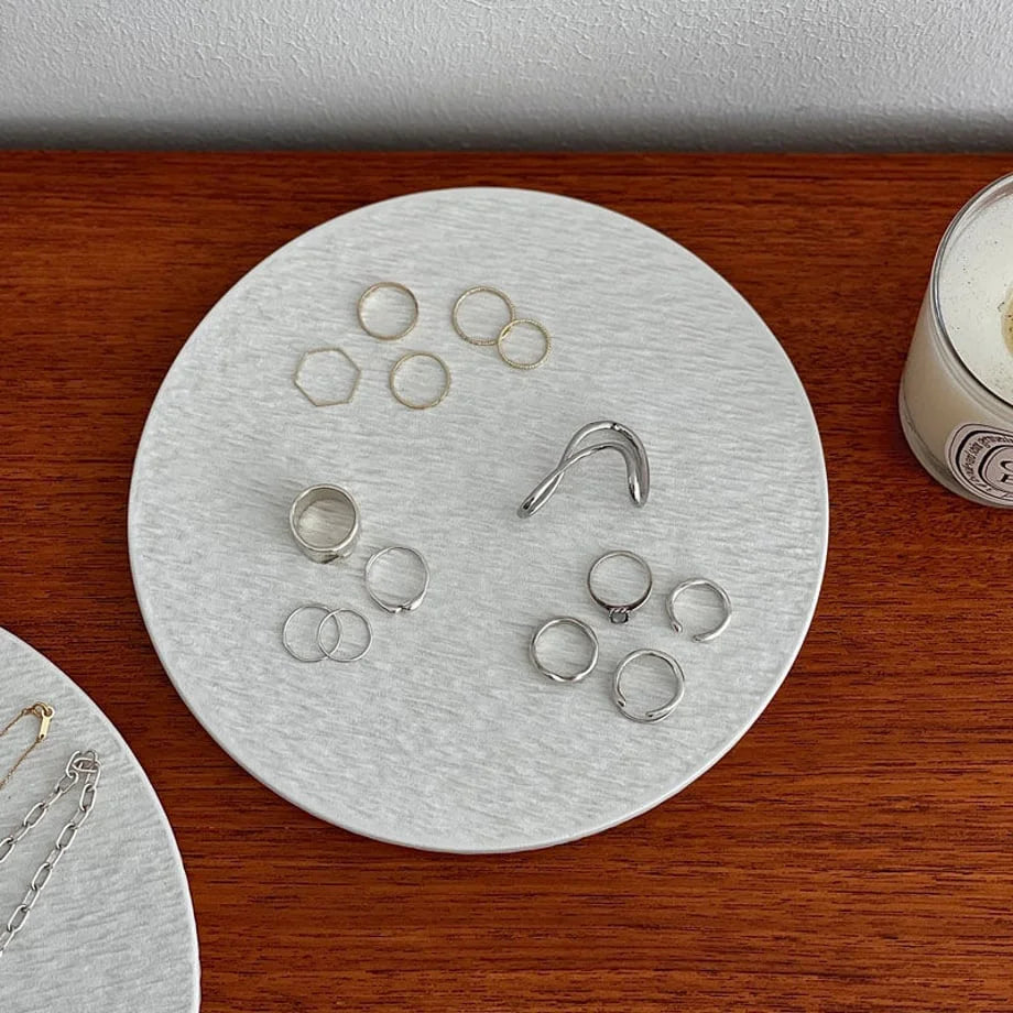 Detail shot of the smallest ceramic ring dish, showing its textured surface holding various silver and gold rings. - RoomDen