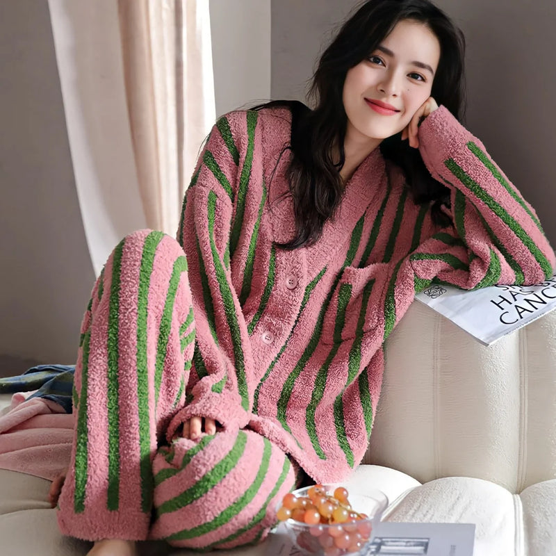 Model relaxing on a couch in the Plush Bold Striped Fleece Pajama Set in pink and green - RoomDen.