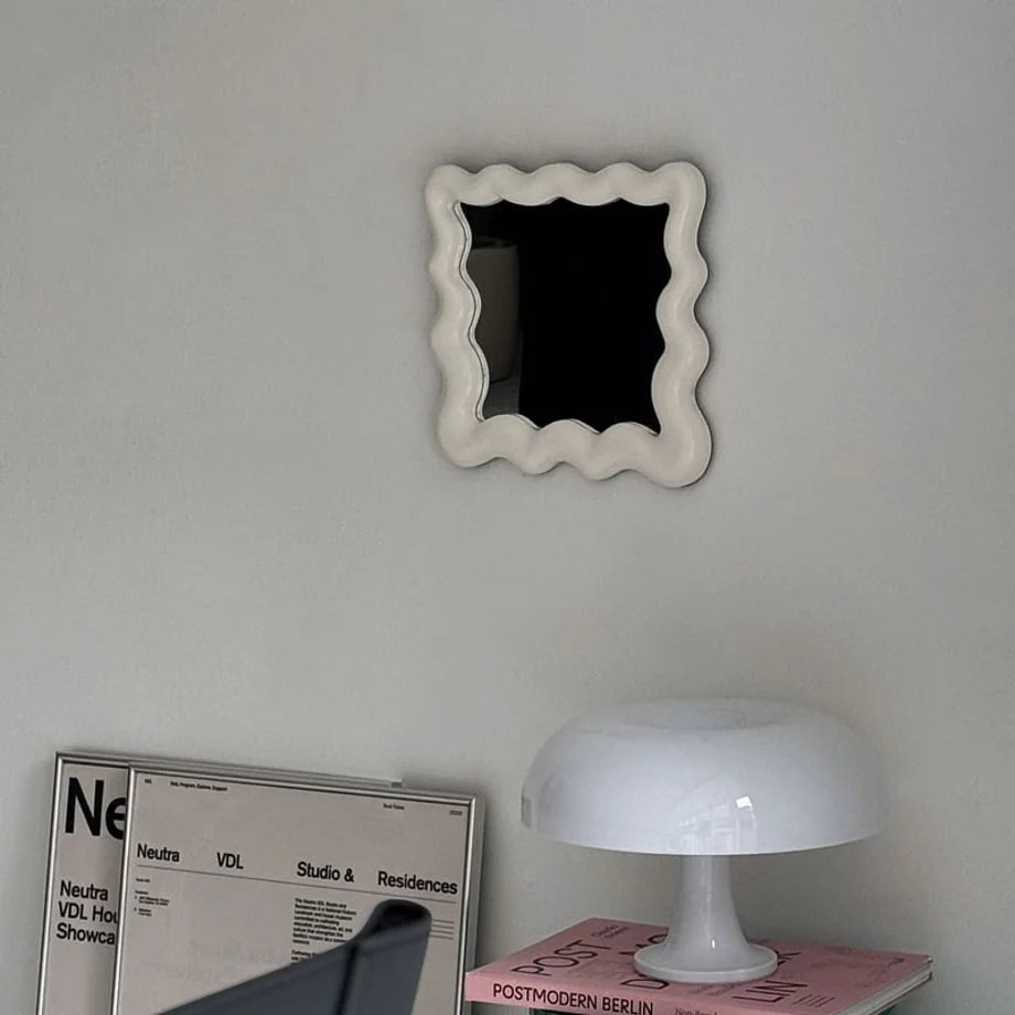 Front view of the off-white squiggle mirror hanging in a modern, minimalist room - RoomDen