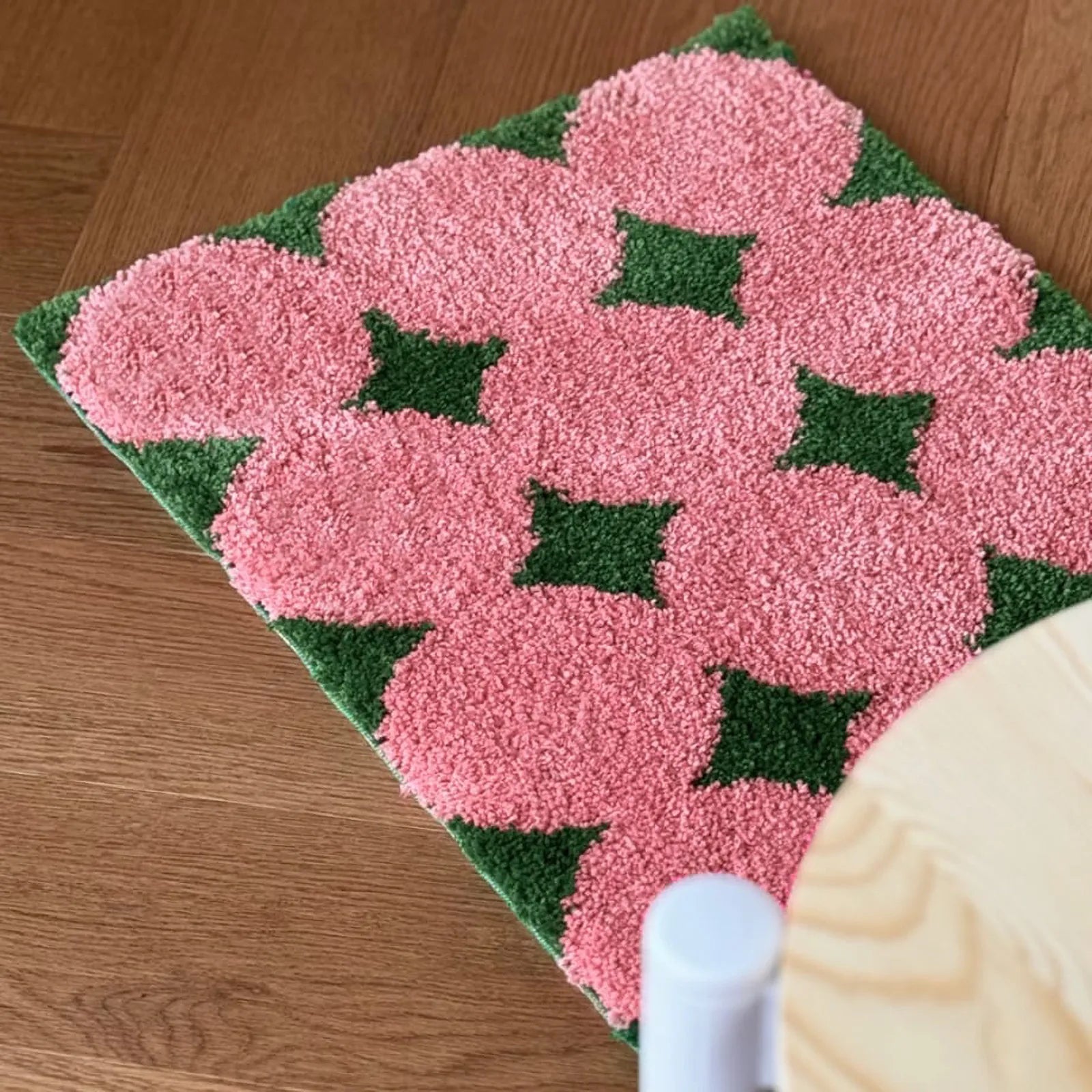 Top down view of pink flower field pattern rug on floor - RoomDen