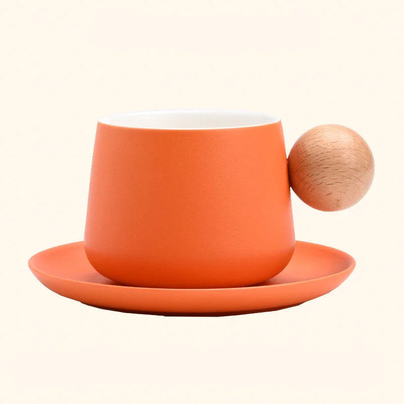 A studio shot of the Orange Frosted Ceramic Mug and Saucer Set with a wooden ball handle. - RoomDen