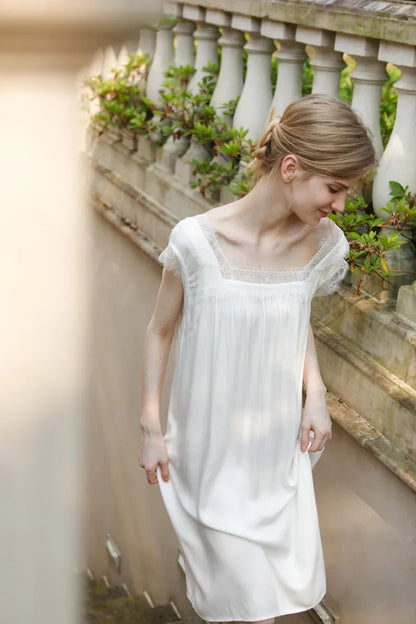 Model walking down stone stairs in vintage style white cotton sleep dress - RoomDen
