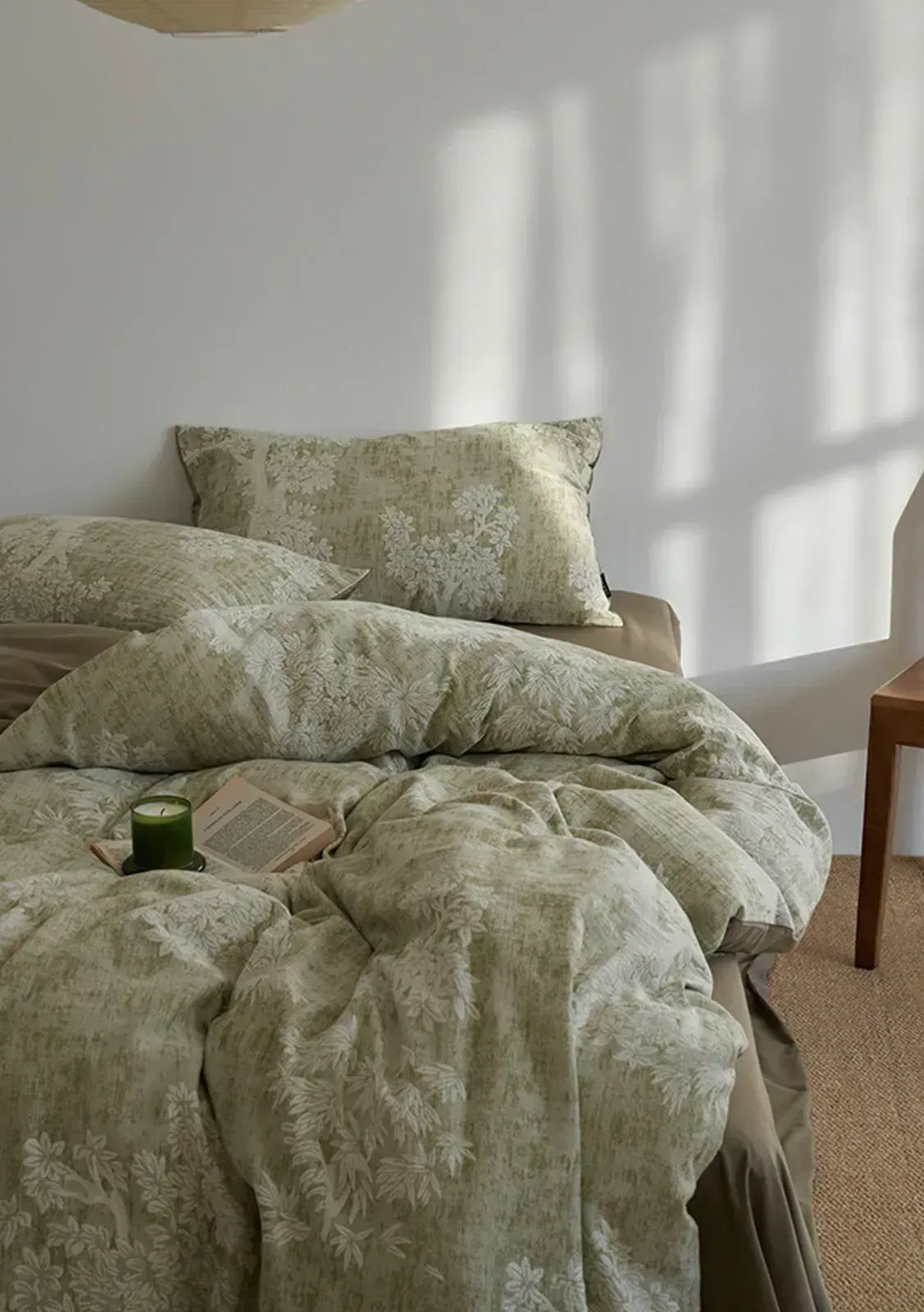 A cozy, slightly rumpled bed featuring the sage green Jacquard Botanical Washed Cotton Bedding Set with soft morning light - RoomDen.