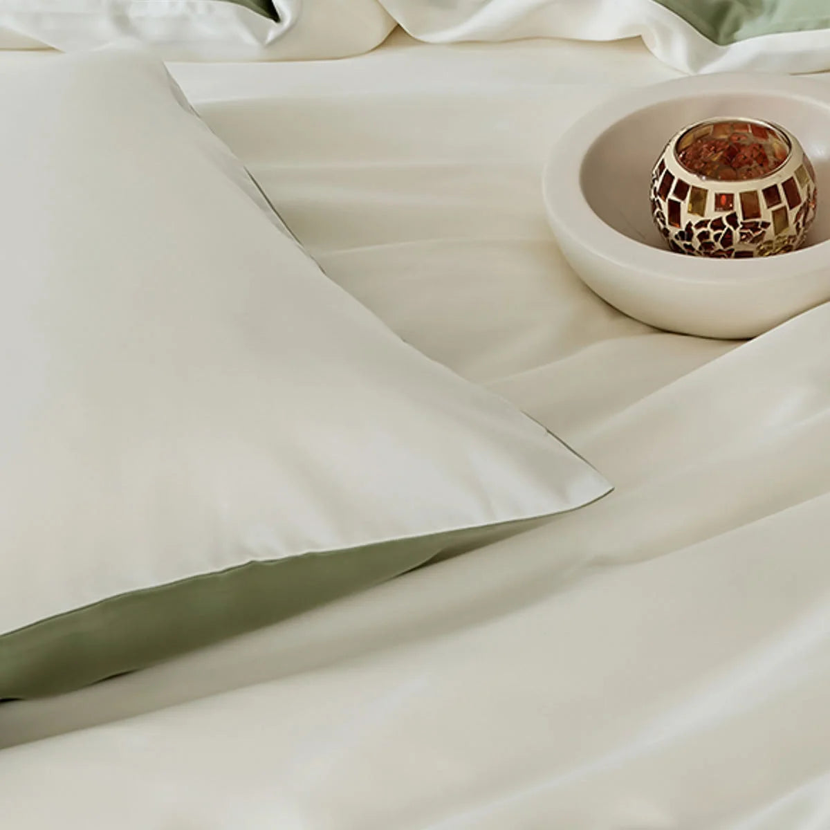 Close-up view of the pillowcase from the White & Sage Green Tencel bedding set.