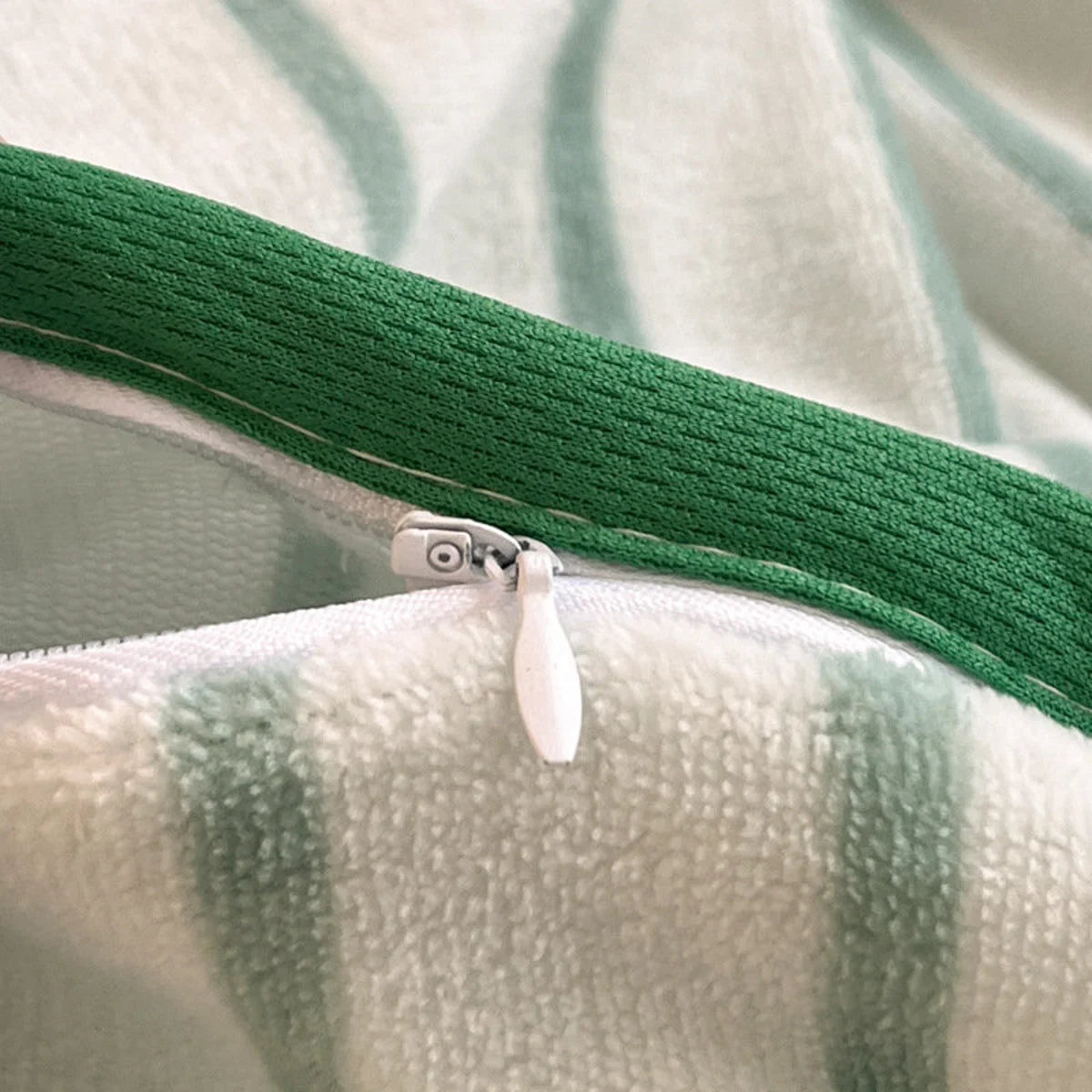 Detail shot of the white zipper and green trim on the striped flannel fleece duvet cover. - RoomDen