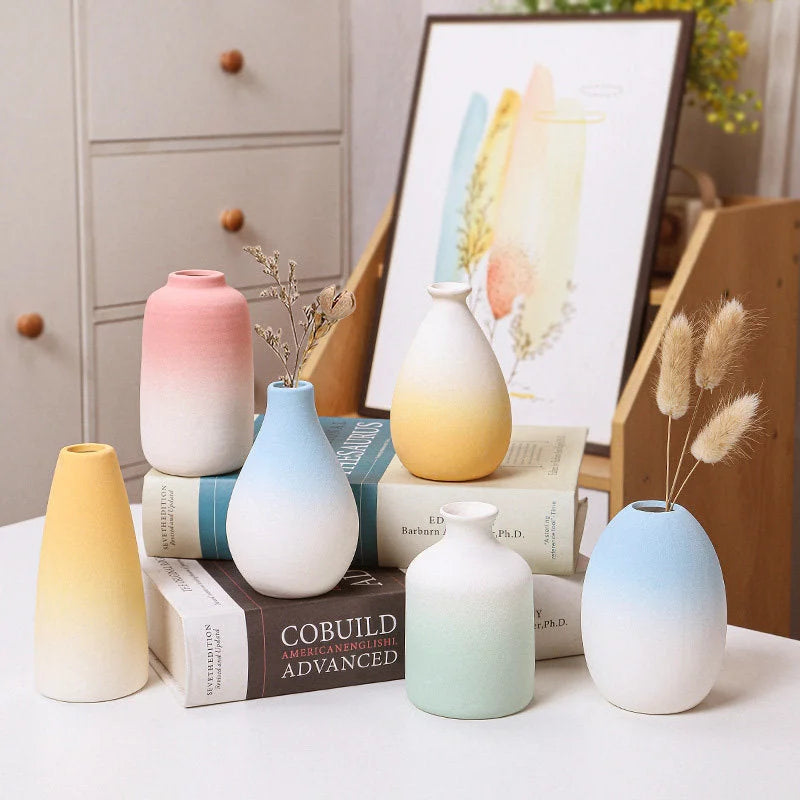 Collection of pastel ombre frosted ceramic vases in various shapes and colors on a desk - RoomDen.