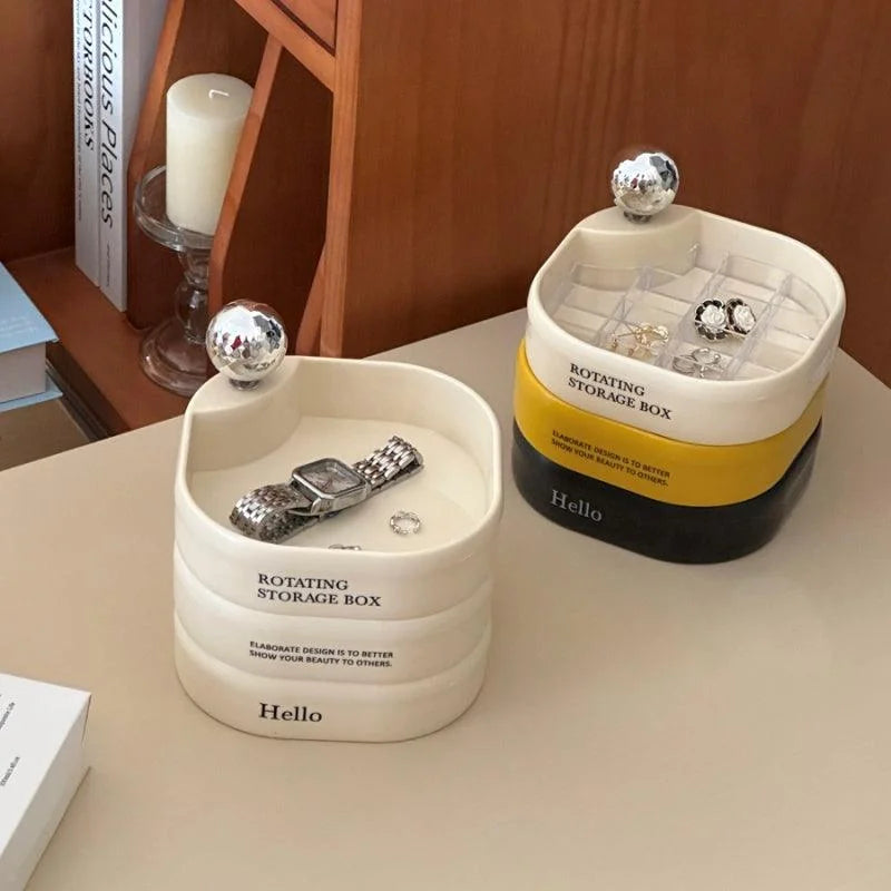 Two rotating jewelry organizers, one creamy white and one tricolor, on a wooden desk. - RoomDen