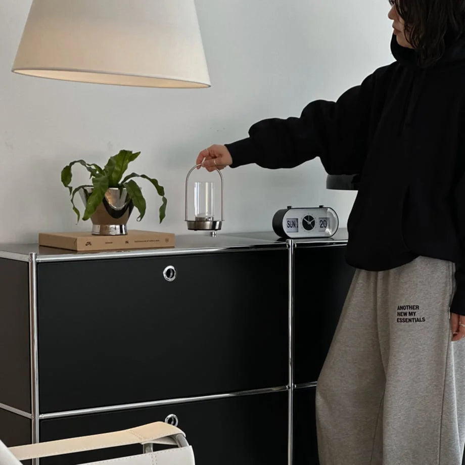 A person holding the Minimalist Arch Metal Table Lamp by its handle in a Japandi-style room. - RoomDen
