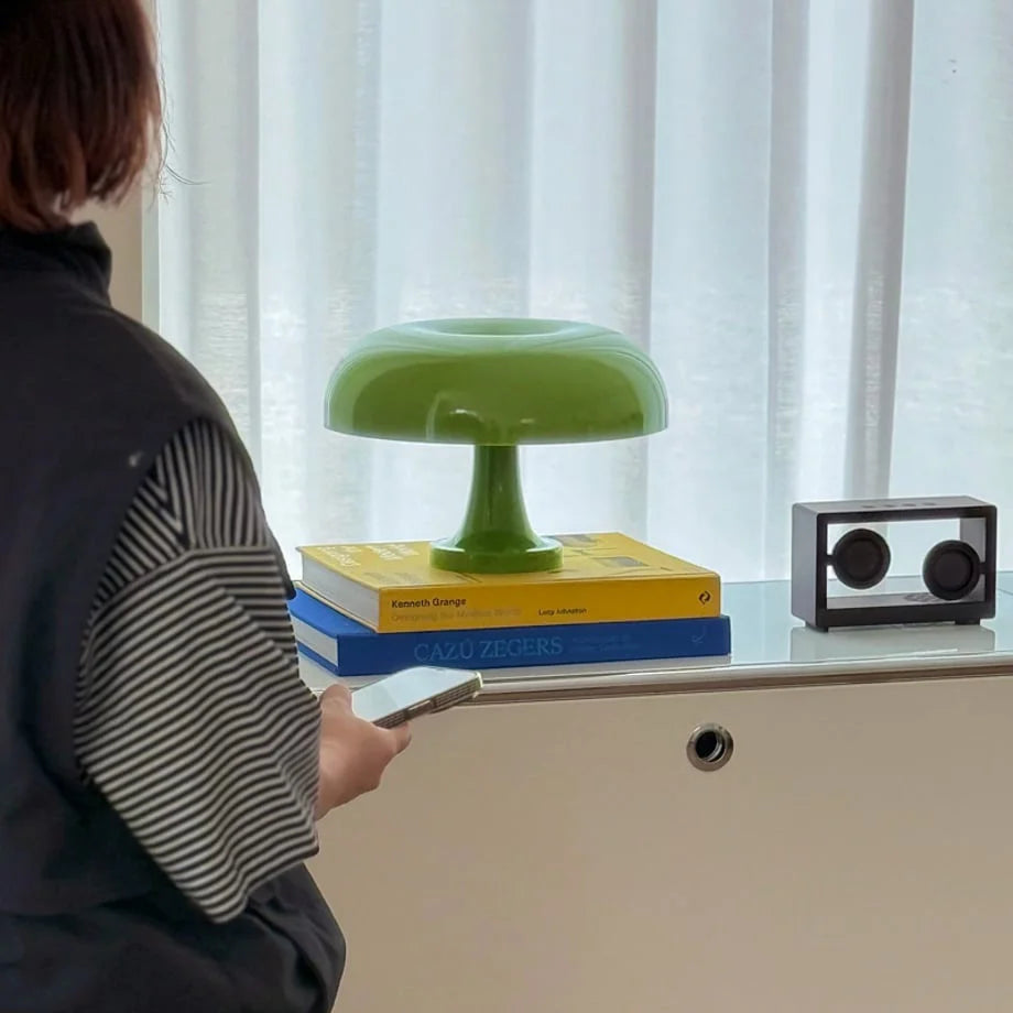 Person holding a phone next to the lime green mushroom lamp on a white cabinet - RoomDen.