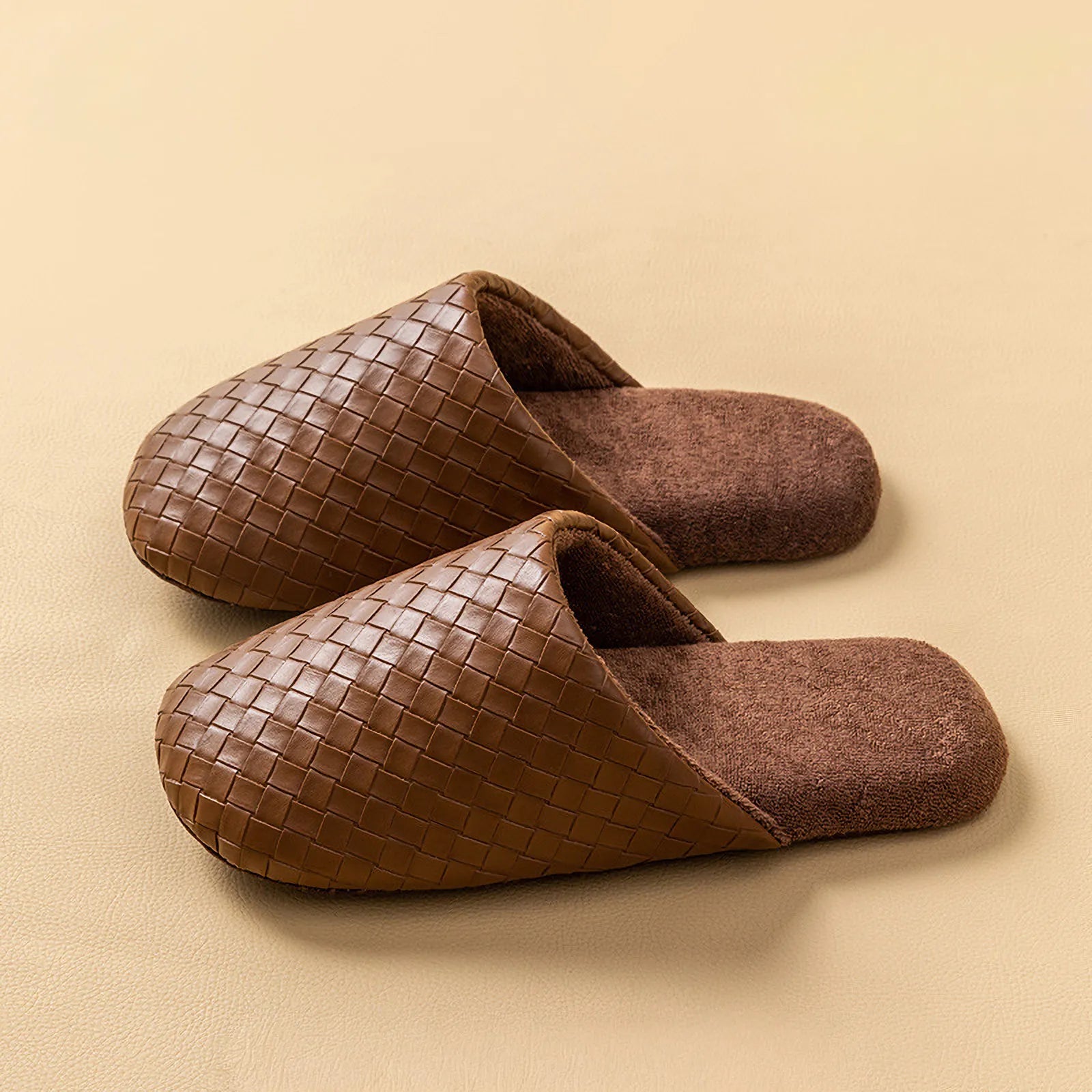 Pair of dark brown woven texture slippers with plush lining on beige surface