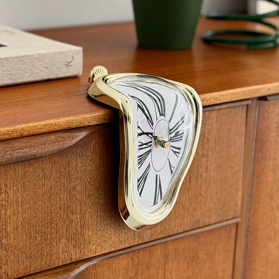 Close-up of the gold melting clock's glossy finish against the wood grain.