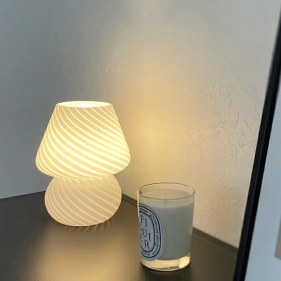 Swirled Glass Mushroom Lamp emitting a warm glow on a black console table - RoomDen.