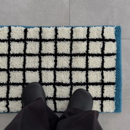 Top-down perspective of black shoes standing on the soft white and black grid rug - RoomDen