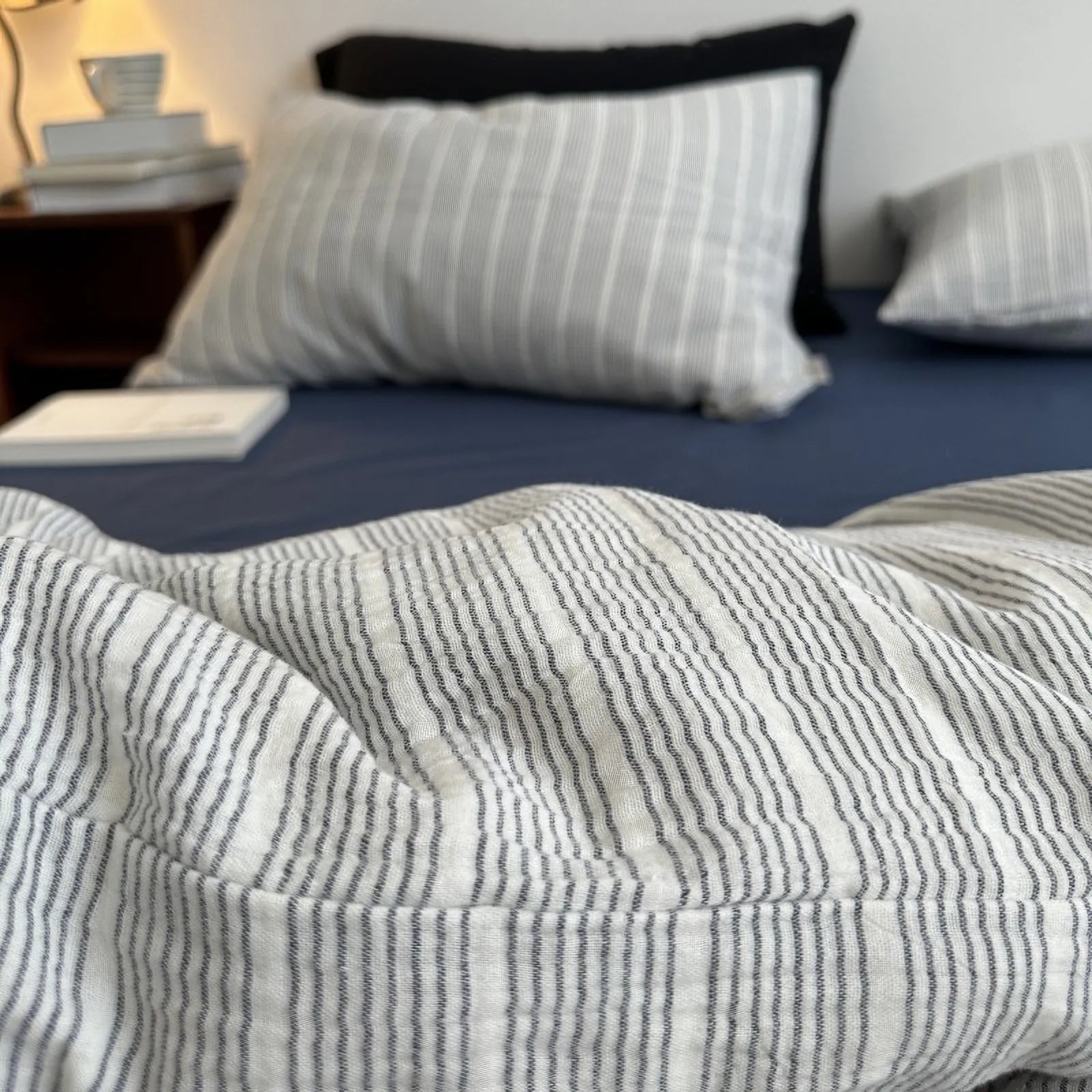 Detailed view of the grey pinstripe washed cotton bedding's texture, with the bed and pillows in soft focus.