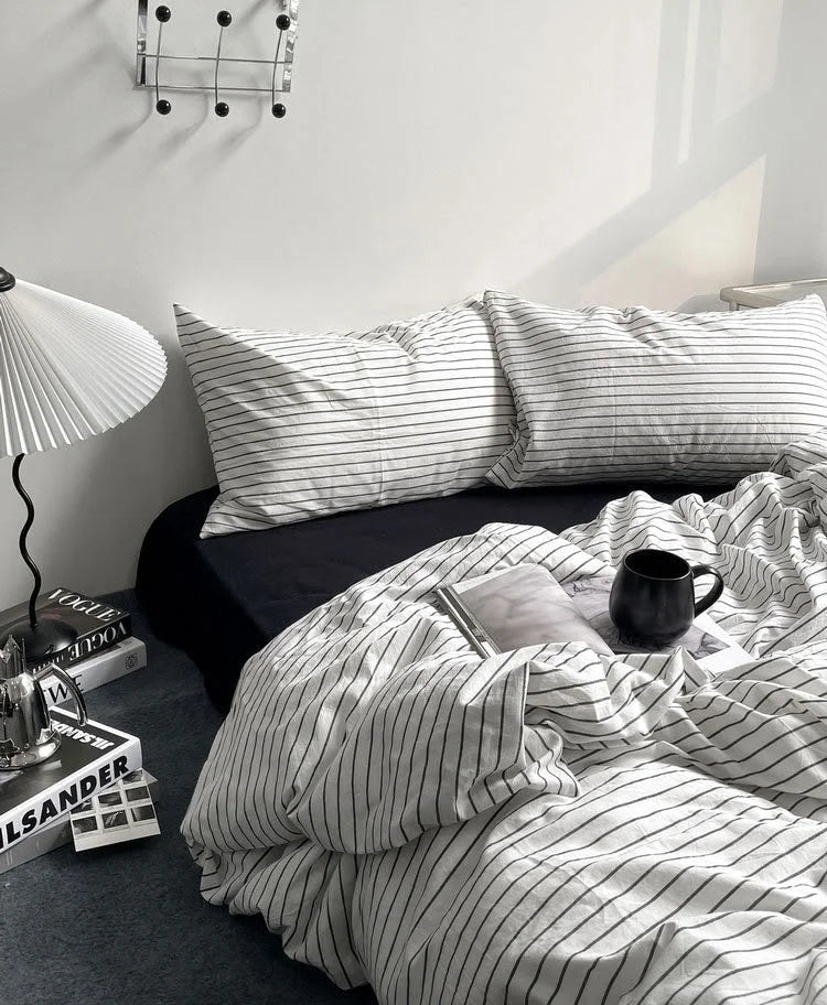 The pinstripe duvet cover and pillowcases on a bed with a black sheet, showing a clean and modern bedroom setting. - RoomDen