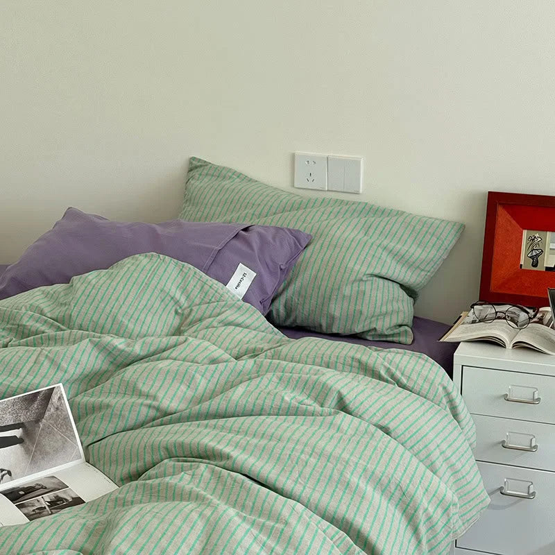 Lifestyle shot of the Mint & Lavender Striped Washed Cotton Bedding with a laptop, creating a cozy work-from-bed scene - RoomDen.