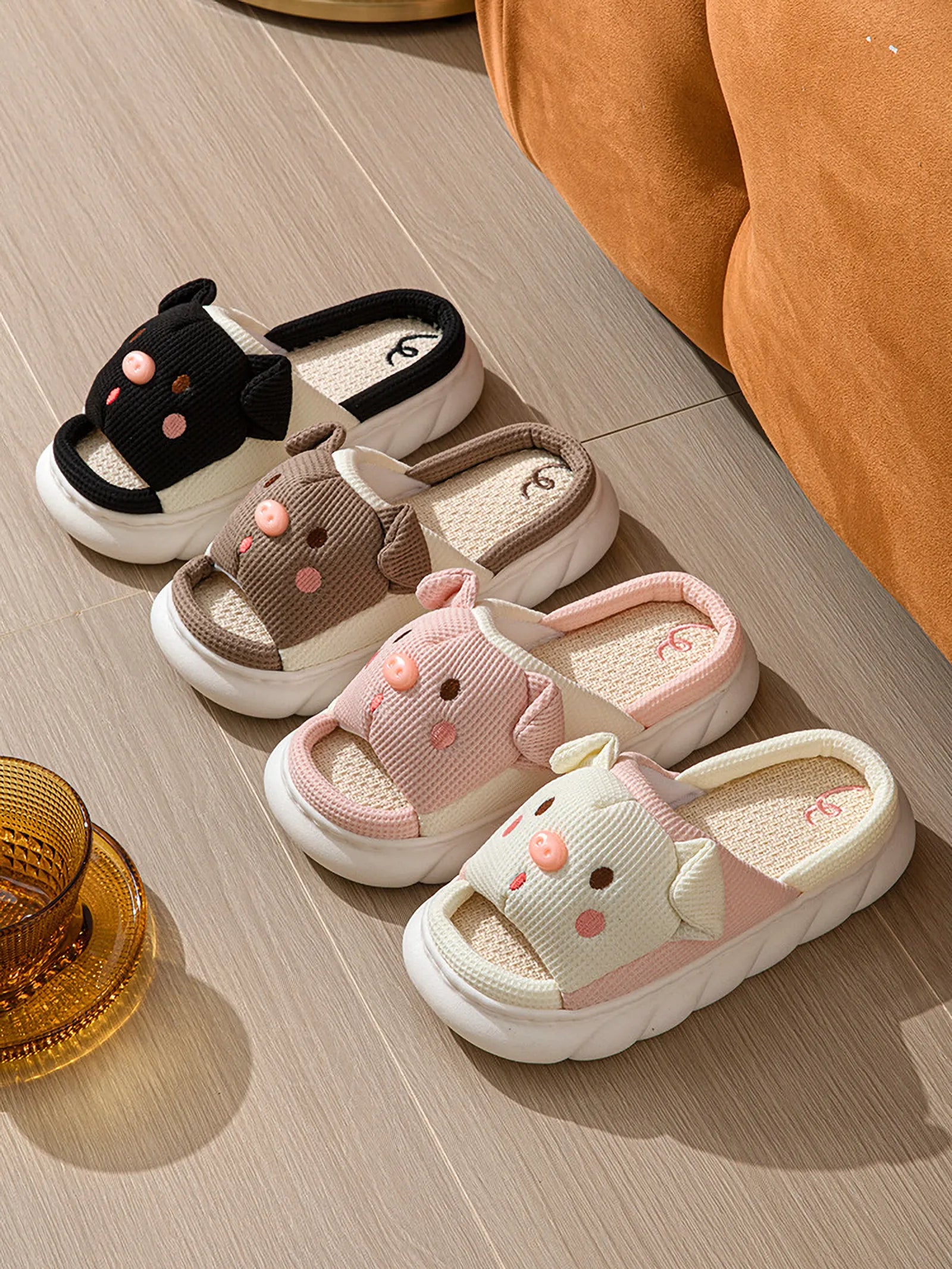 Group of Black, Brown, Pink, and White Waffle Textured Embroidered Pig Linen House Slippers on a wooden floor - RoomDen