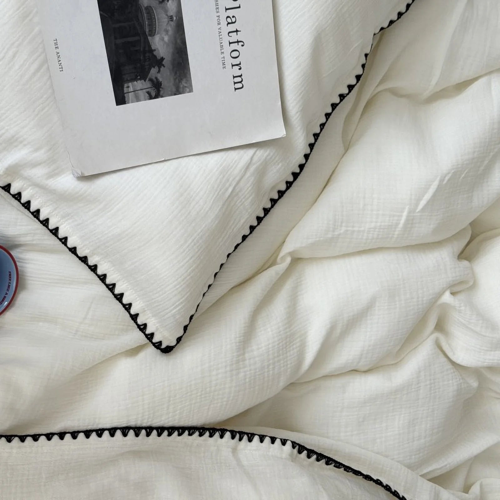 Detail of the black embroidered edge on the soft, crinkled cream white washed cotton duvet cover.