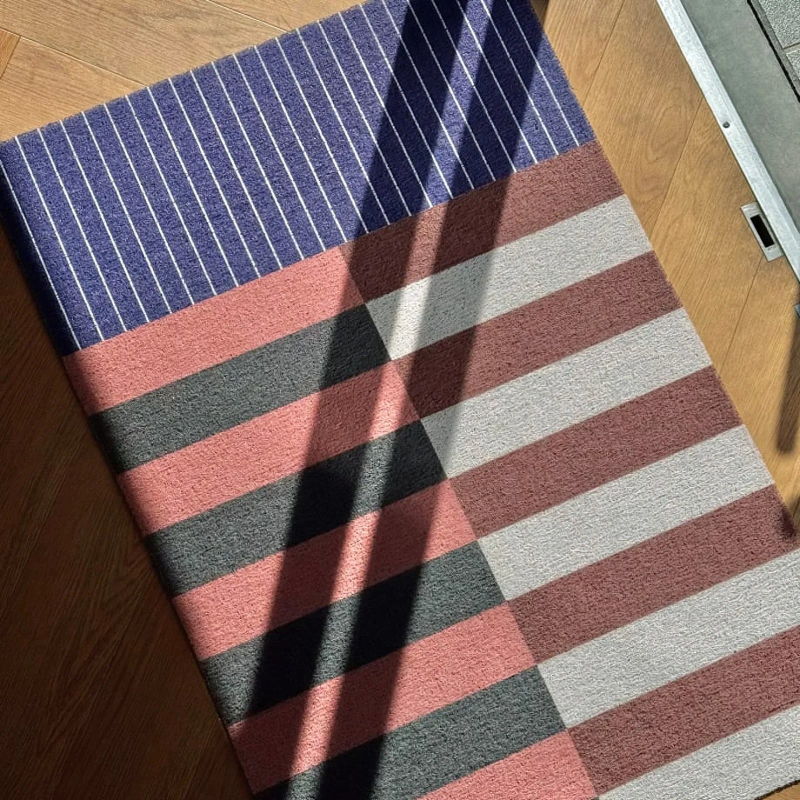 Bauhaus geometric PVC coil doormat in navy and grey stripes at entryway - RoomDen