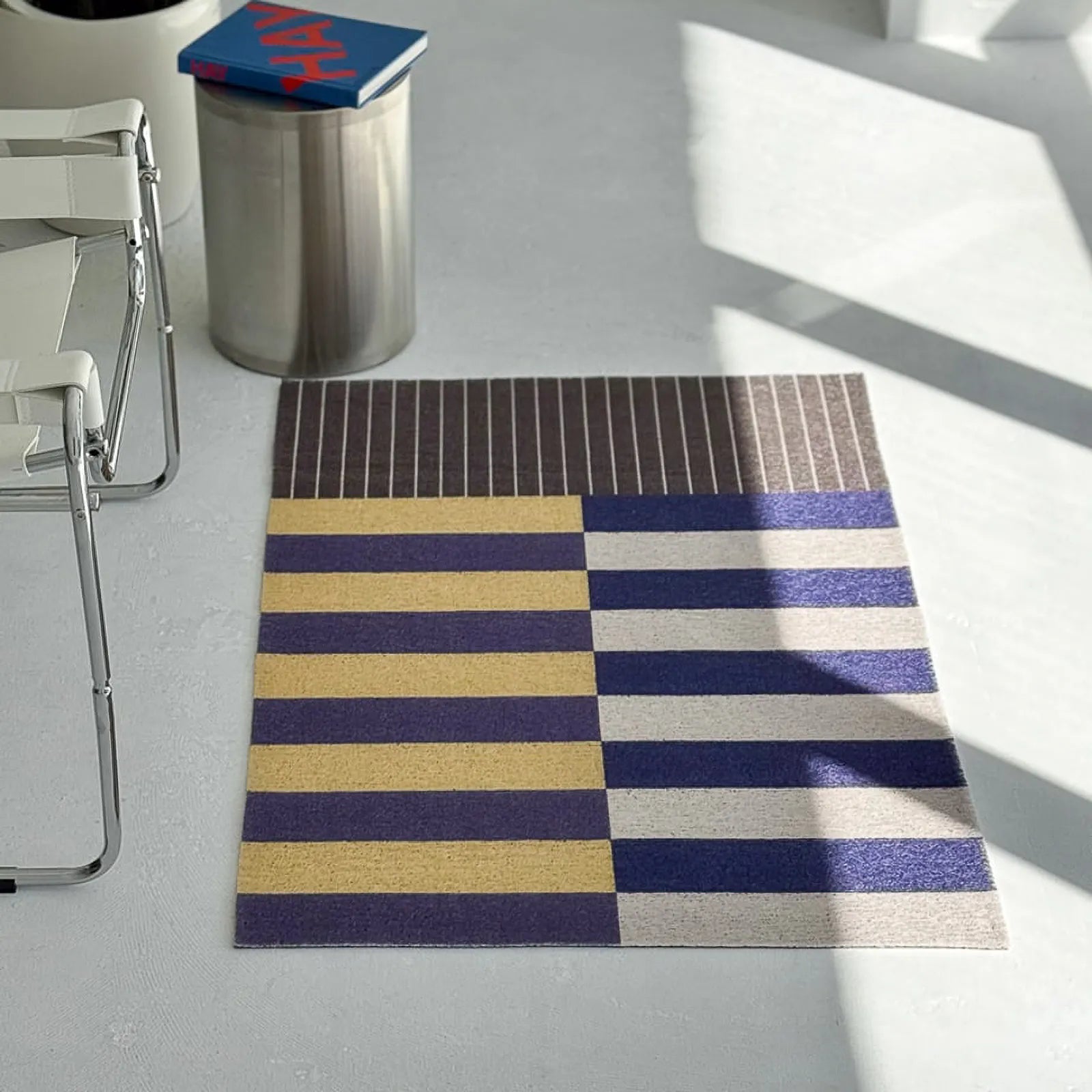Modern art style doormat in navy and yellow stripes on grey floor - RoomDen