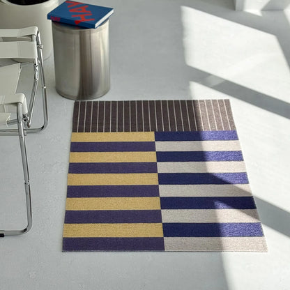 Modern art style doormat in navy and yellow stripes on grey floor - RoomDen