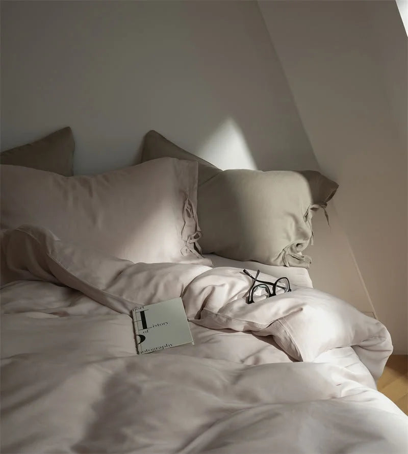 A book and glasses resting on the soft, rumpled Dusty Rose Tencel duvet cover - RoomDen