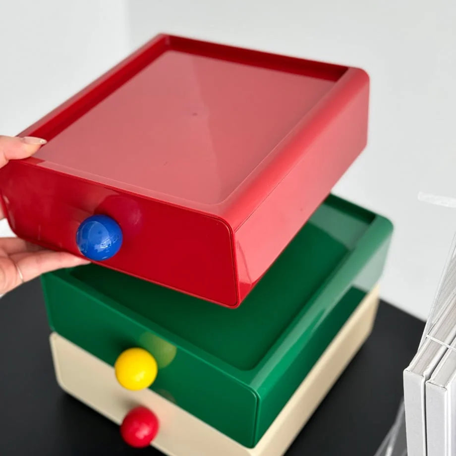 A hand lifting the red drawer from the stack, showing the modular design of the organizer. - RoomDen