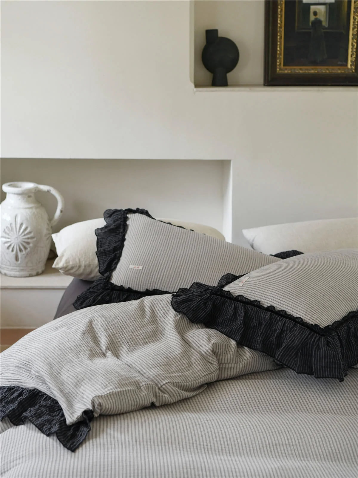 Close-up on the corner of the pillows, showcasing the quality of the black ruffle trim on the pinstripe bedding. - RoomDen