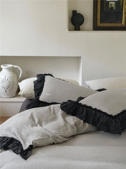 Close-up on the corner of the pillows, showcasing the quality of the black ruffle trim on the pinstripe bedding. - RoomDen