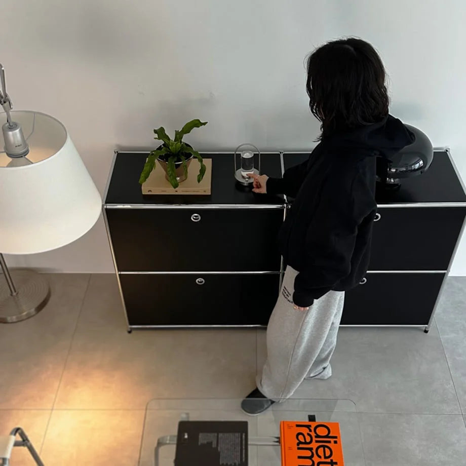 A person placing the portable metal table lamp on a black modern credenza. - RoomDen