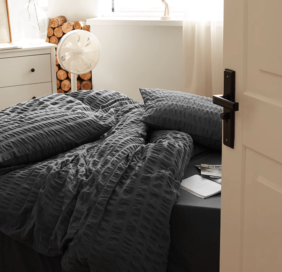 Marlon Seersucker Cotton Bedding Set – slate-grey bedding in a softly lit room beside a window - Roomden