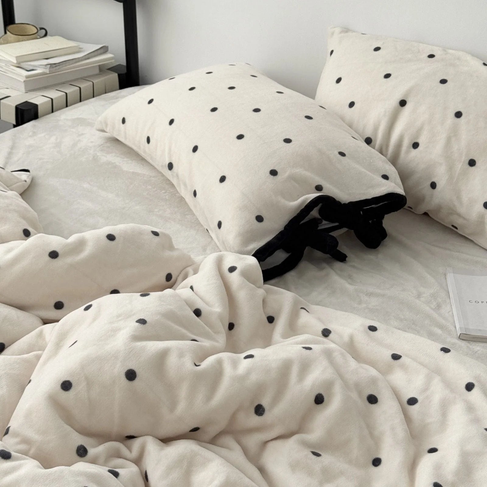 Close-up of the Creamy White Polka Dot pillows with black tie details, showing the plush material.