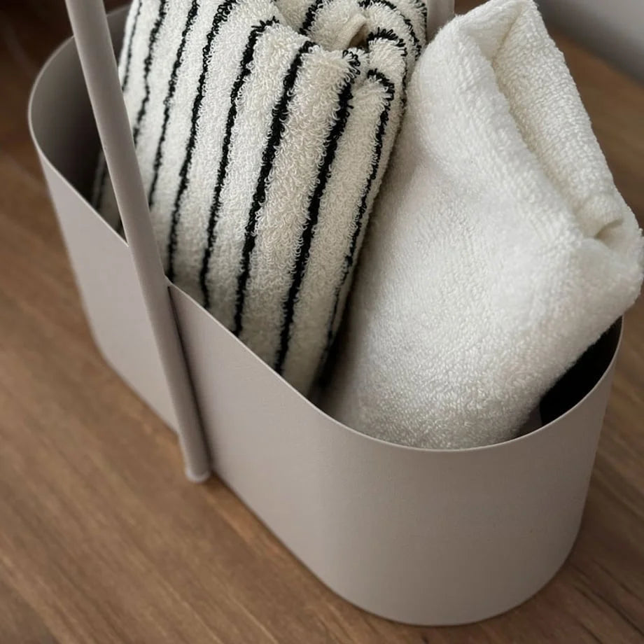 Close-up on the rolled towels inside the beige metal organizer, showing the caddy's capacity. - RoomDen