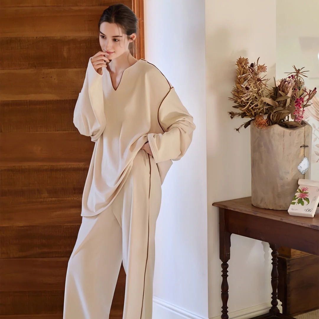 Model wearing the soft piped plush pajama set, leaning against a wooden wall. - RoomDen