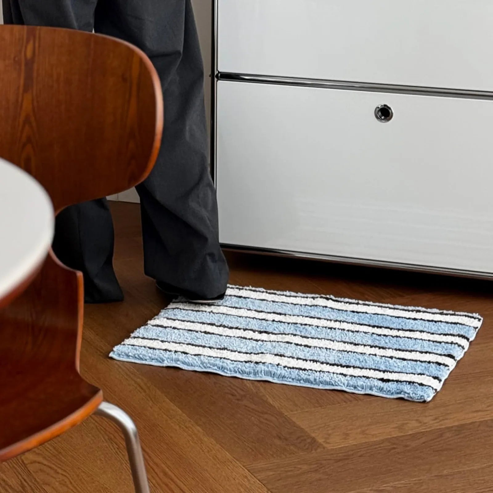 Close-up usage shot showing person standing on soft shaggy striped rug - RoomDen
