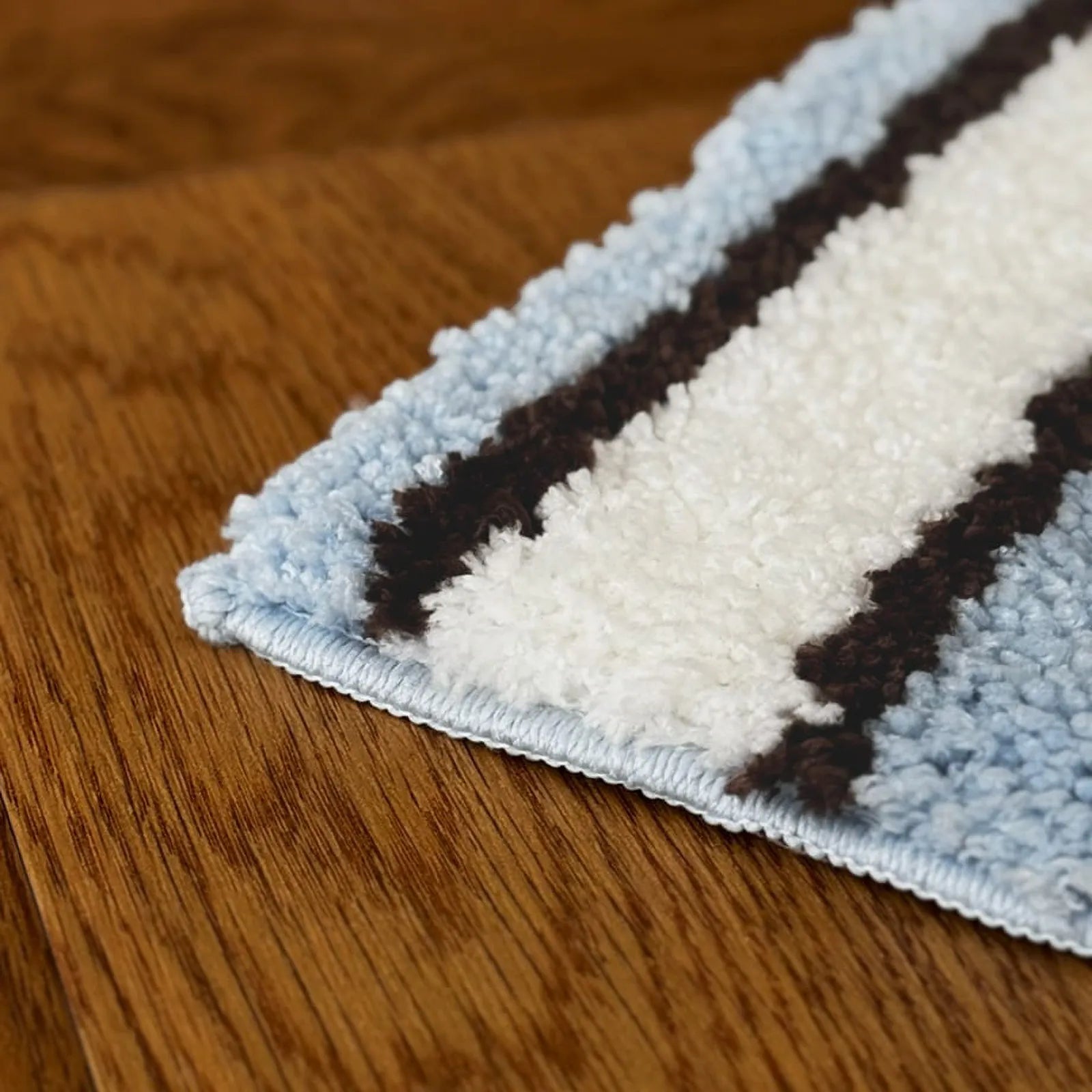 Extreme close-up of rug edge showing tufted microfiber texture - RoomDen