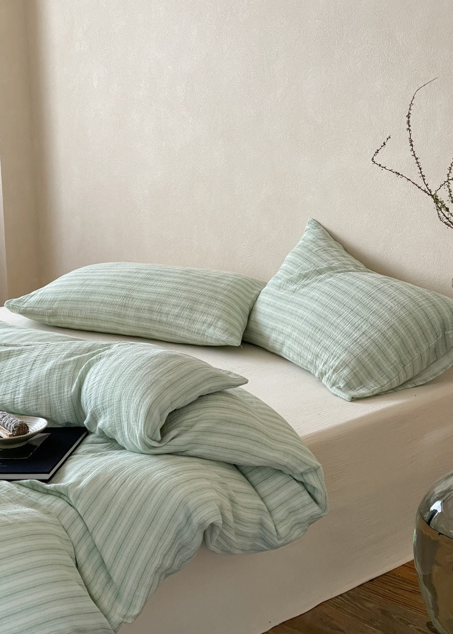 Halden Striped Cotton Double Gauze Bedding Set – sage pillows and folded duvet in soft light - Roomden