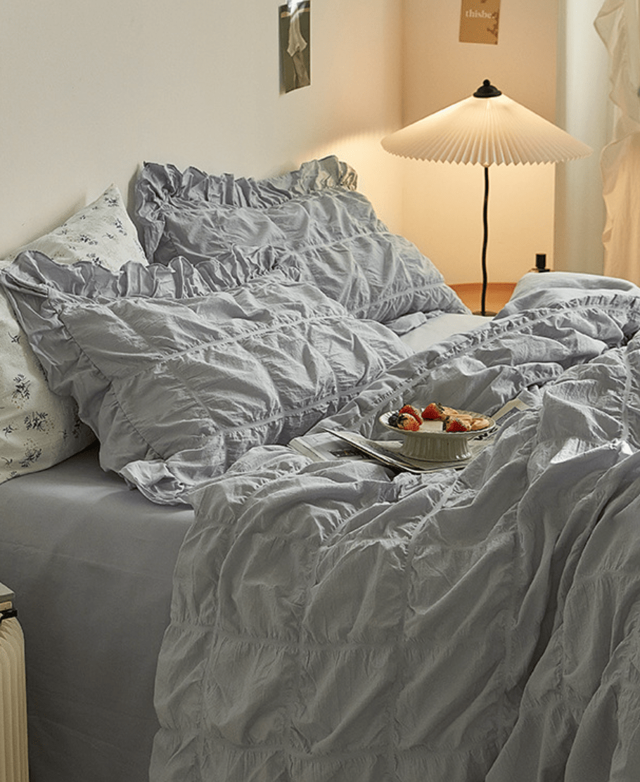 Odessa Ruffled Cotton Blend Bedding Set – silver-blue ruffled bed viewed from the side beneath framed artwork - Roomden