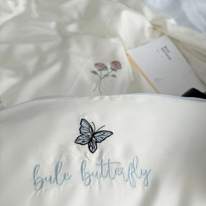 Detailed shot of the "blue butterfly" text embroidery on the Cream White pillowcase, made from silky Tencel fabric.