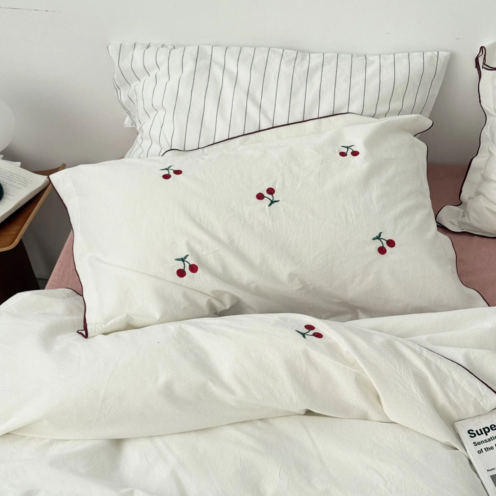 Full view of the Embroidered Cherry Washed Cotton Bedding Set in pure white on a bed with a pink sheet.