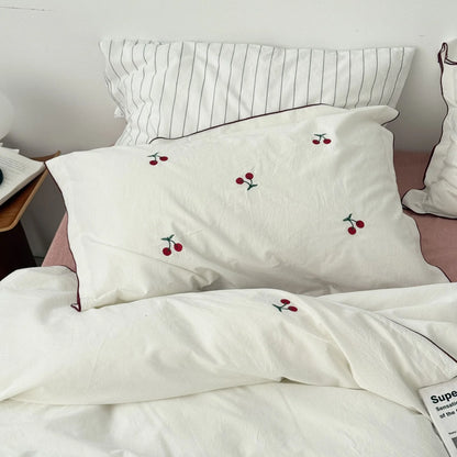 Full view of the Embroidered Cherry Washed Cotton Bedding Set in pure white on a bed with a pink sheet.
