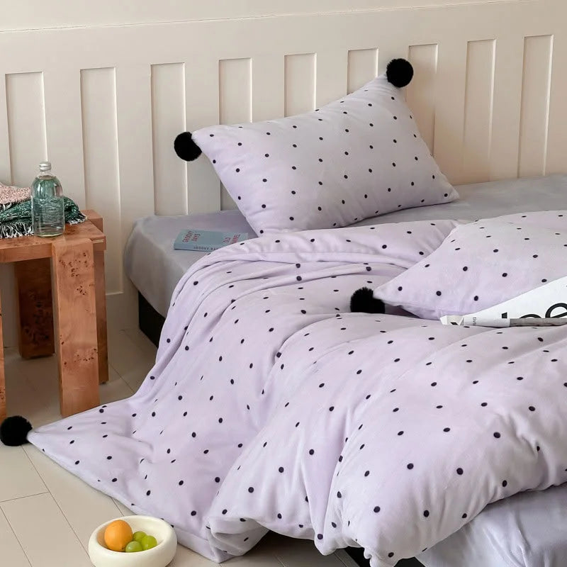 The Lavender Polka Dot Pom Pom Velvet Bedding Set variant shown on a bed, highlighting its soft purple hue. - RoomDen