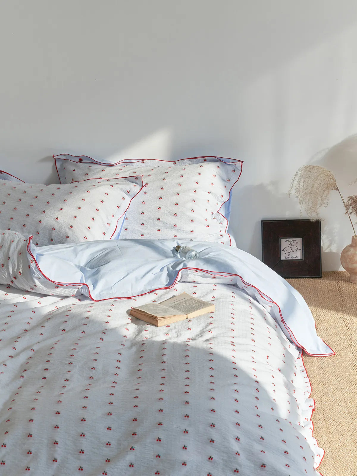 Coquette style bedroom featuring the Ruffled Cherry Print Bedding Set with an open book resting on it. - RoomDen