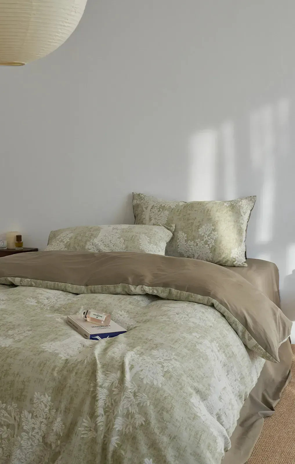 A neatly made bed with the sage green Jacquard Botanical Washed Cotton Bedding Set in a bright, minimalist room - RoomDen.