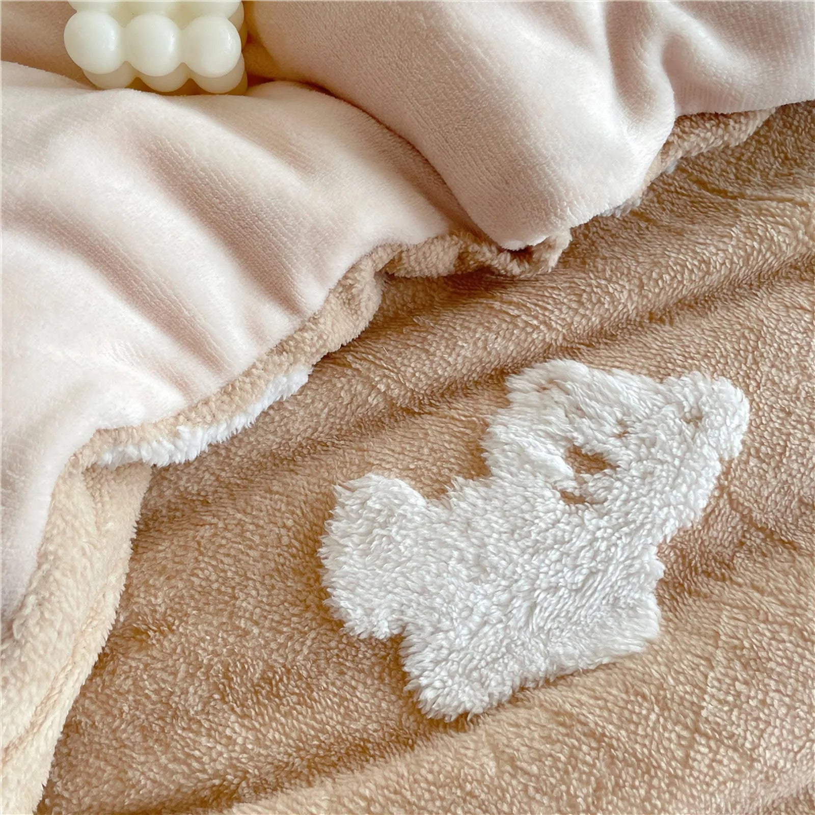 Extreme close-up on a white fluffy teddy bear appliqué on the creamy beige flannel fleece material. - RoomDen