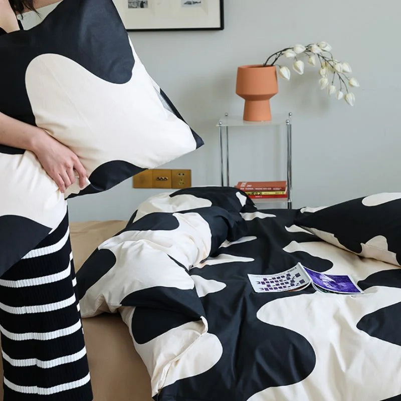 Person holding up a pillowcase with the black and beige wavy abstract pattern, showing the design clearly - RoomDen