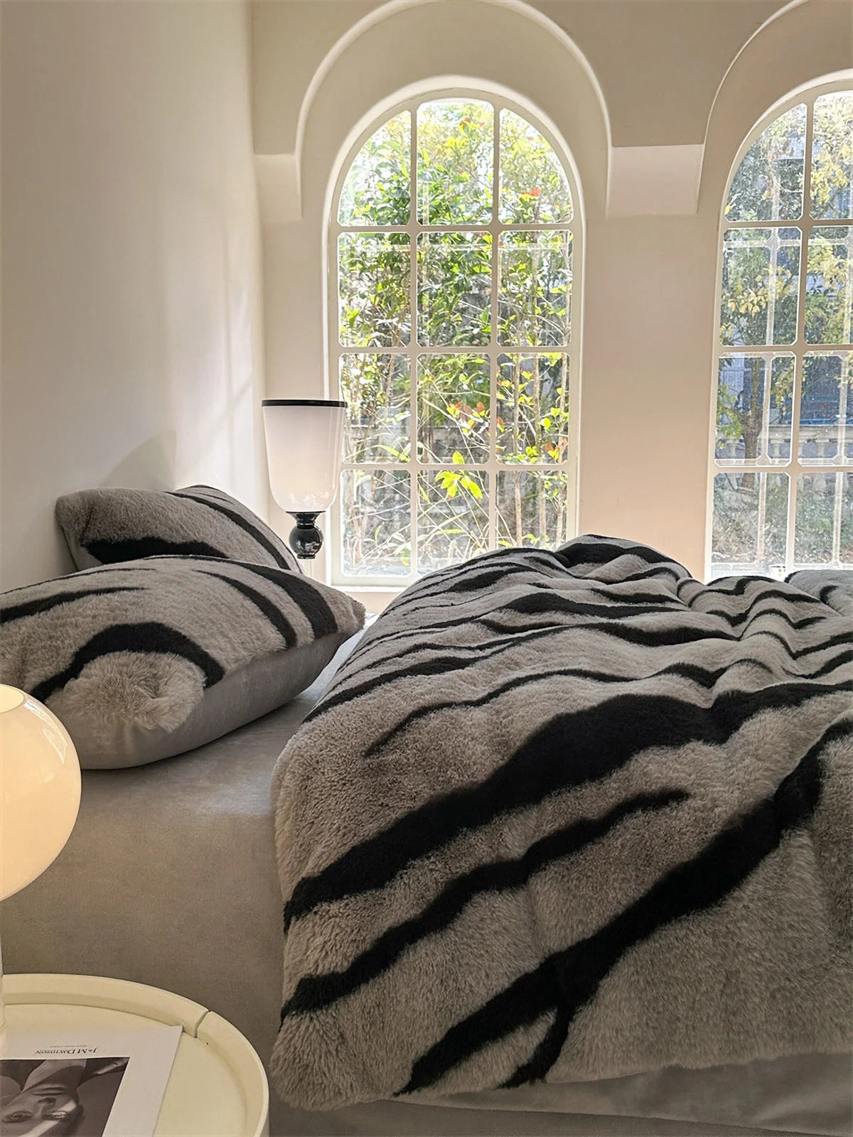 The Ash Grey Tiger Stripe bedding in a brightly lit room with arched windows, creating a serene and stylish atmosphere. - RoomDen